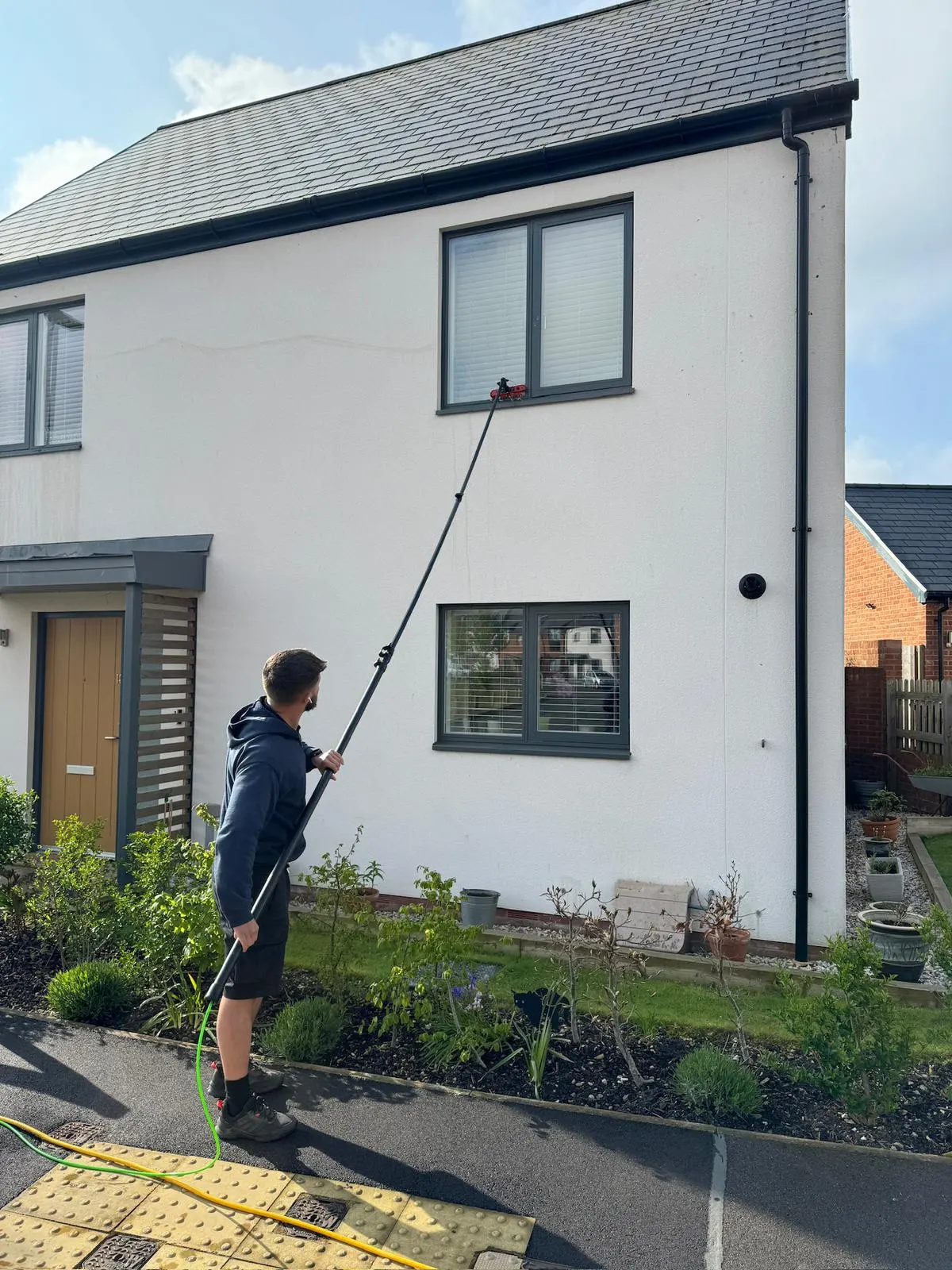 Dorset Window Cleaning team member using a pure-water pole on a modern home in Dorset